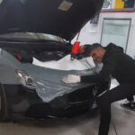 Operatore di Raia srl applica adesivo su una Maserati.