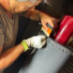Operatore di Raia srl applica un adesivo tramite paletta.