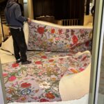 Operatore di Raia srl tiene in mano i teloni per pavimento nel negozio Gucci.